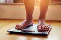 Person Weighing Themselves On Scales